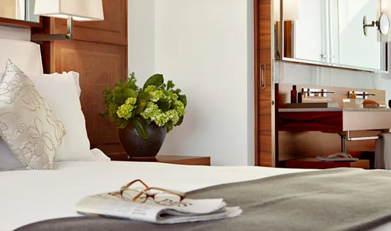 A hotel guest room with a neutral palette and warm wood details.