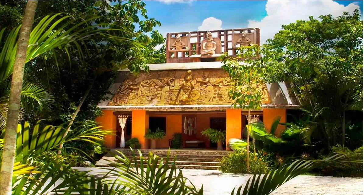 A low-rise villa framed by tropical gardens and a pool.