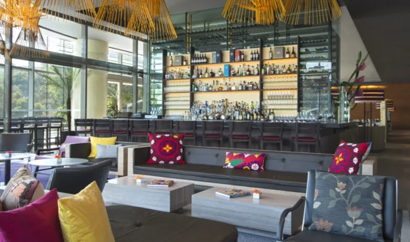 A light-filled contemporary hotel lounge with dark furnishings.