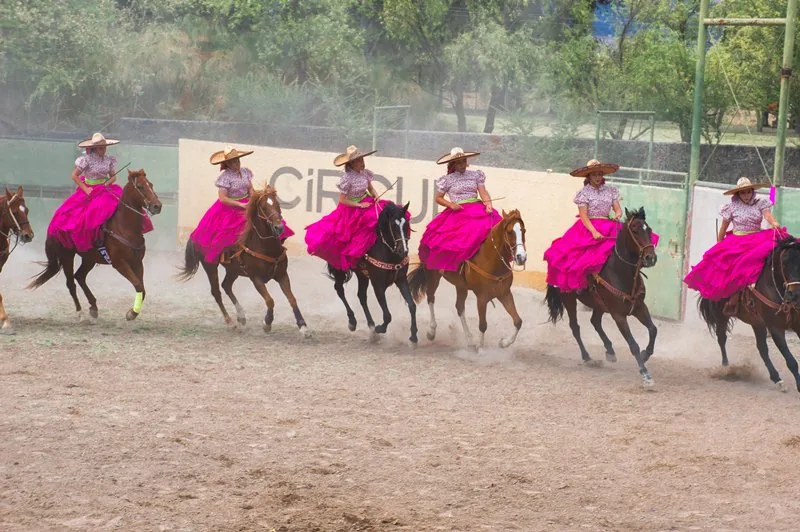 A charro rides a horse in a Mexican rodeo arena.