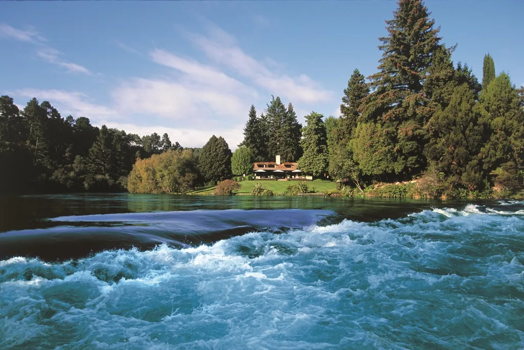 The Waikato River flows past a wooded lodge pavilion.