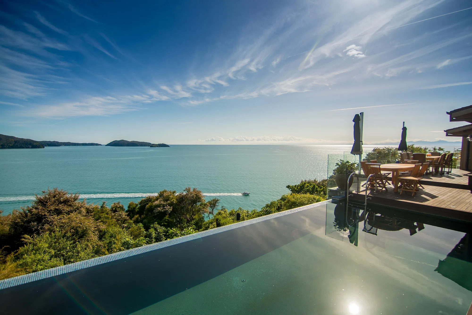 An infinity pool overlooking the sea and forested coastline.