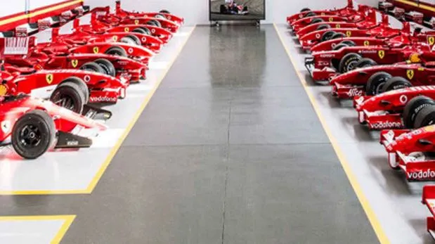 Rows of red Ferrari sports cars on a bright factory floor.