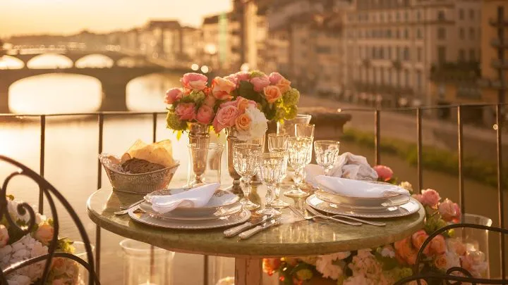 A candlelit dinner table with flowers overlooking Florence’s Ponte Vecchio.