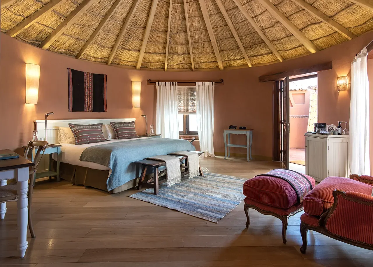 A warm-toned bedroom beneath a circular thatched roof.
