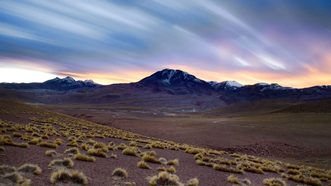 An expansive desert plain and distant mountains at dusk.