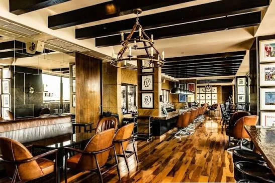 A wood-panelled bar with leather seating and hanging lanterns.