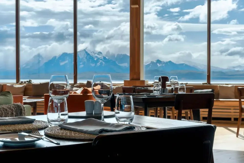 A dining room with panoramic windows overlooking mountains and water.