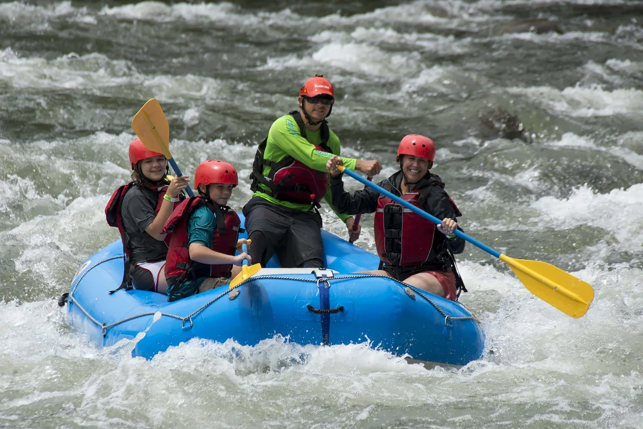 A group paddling a blue raft through white-water rapids.