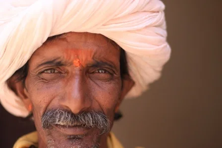 Portrait of a man wearing a pale turban with a red mark on his forehead.