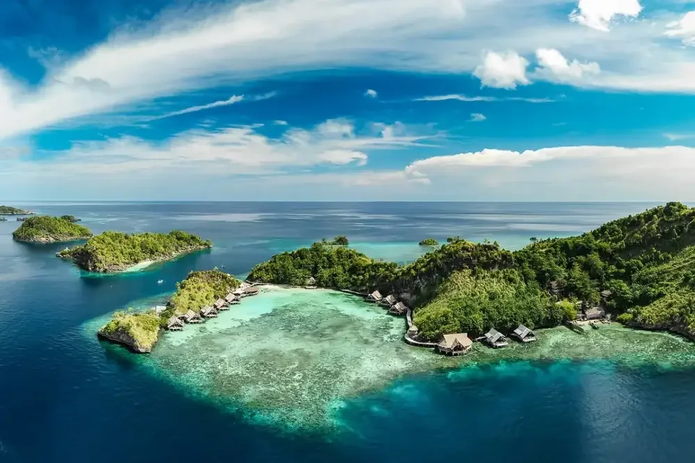 Aerial view of forested tropical islands, turquoise lagoons and a coastal resort.