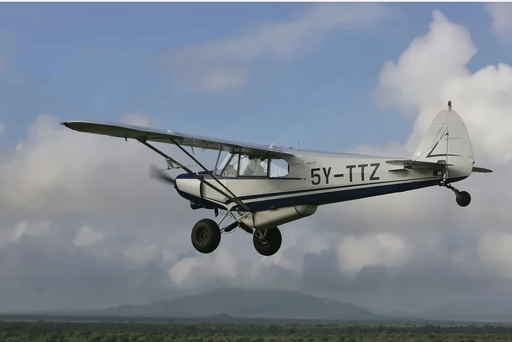A small propeller aircraft flying above distant hills.