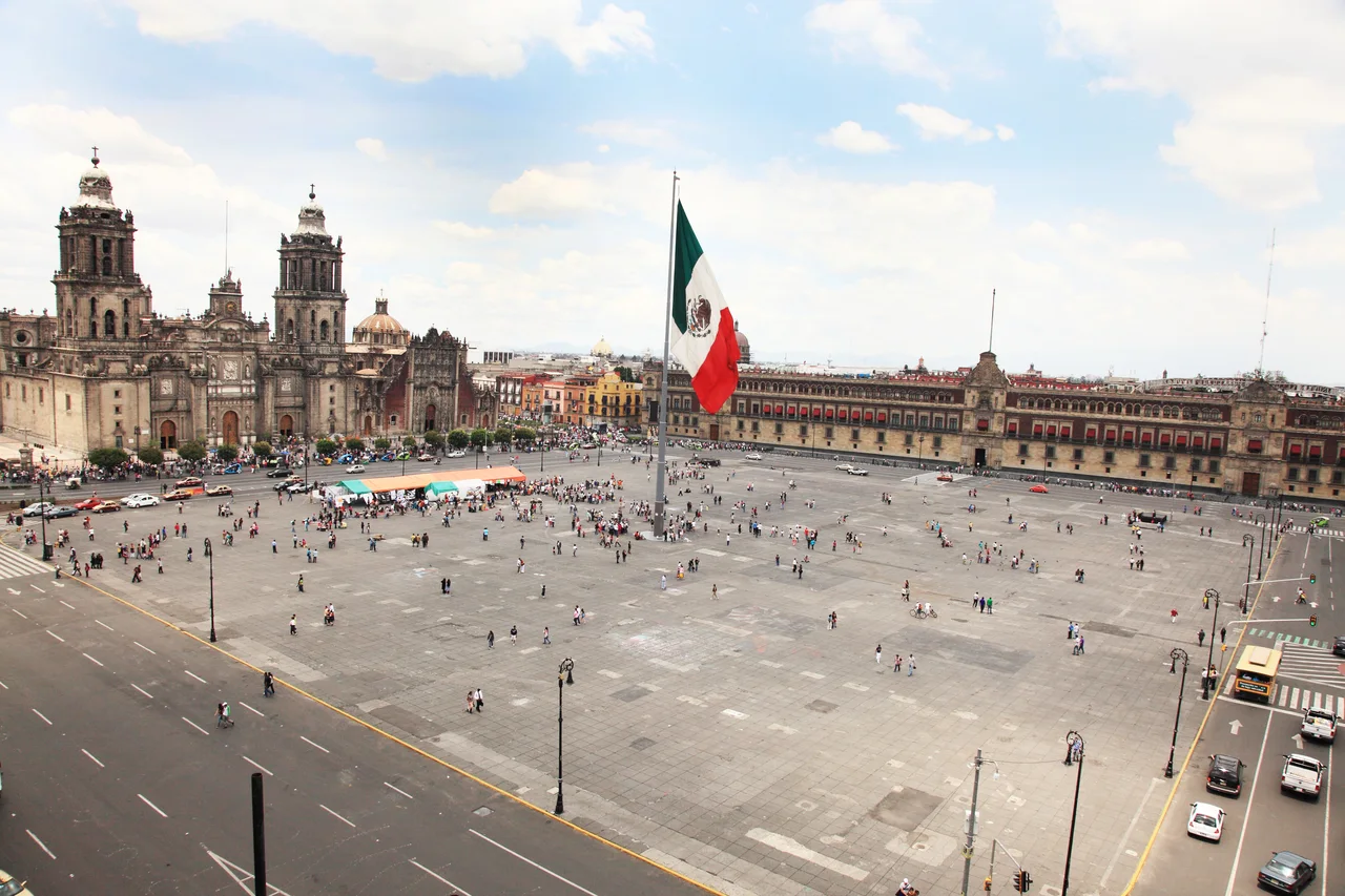Mexico City's central square with its cathedral and a large Mexican flag.