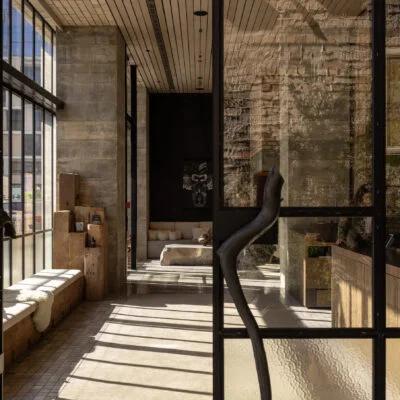 Sunlight falling across a timber staircase beside exposed brick walls and tall windows.
