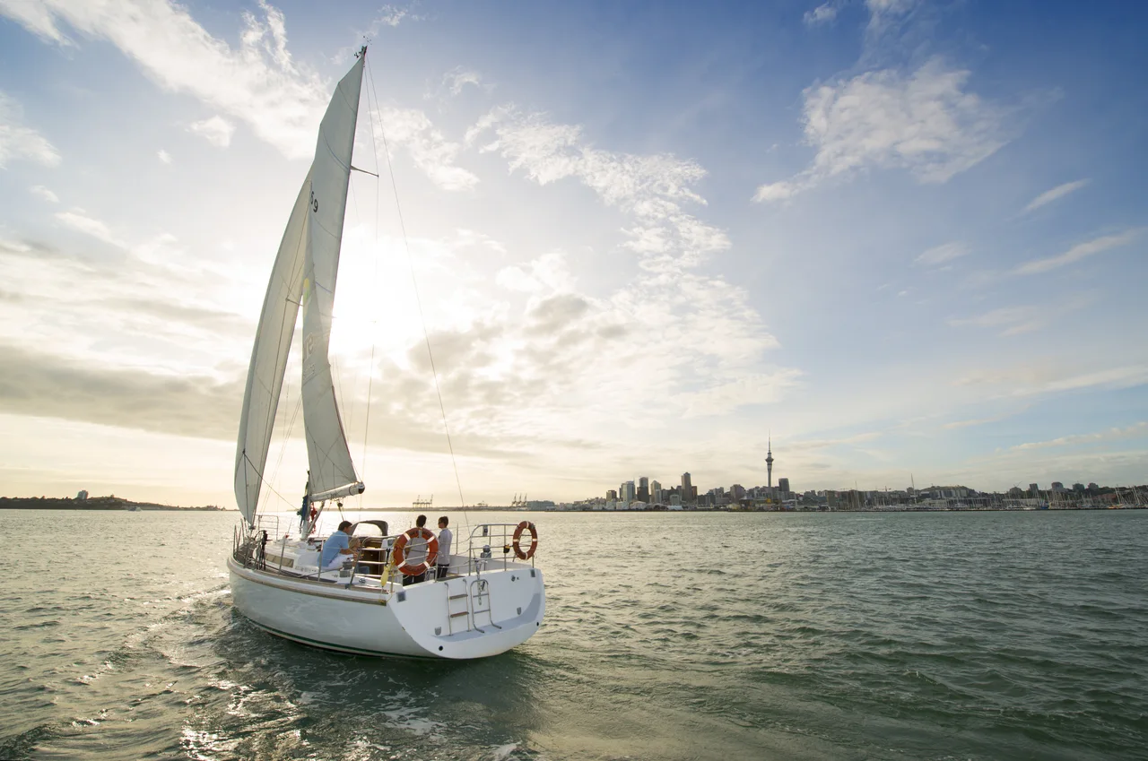 A yacht sailing on Auckland Harbour with the city skyline in the distance.
