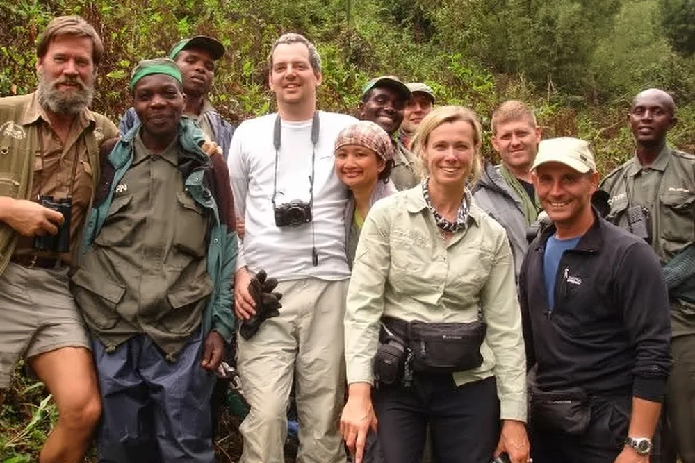 A group of people posing together outdoors in a green forest.