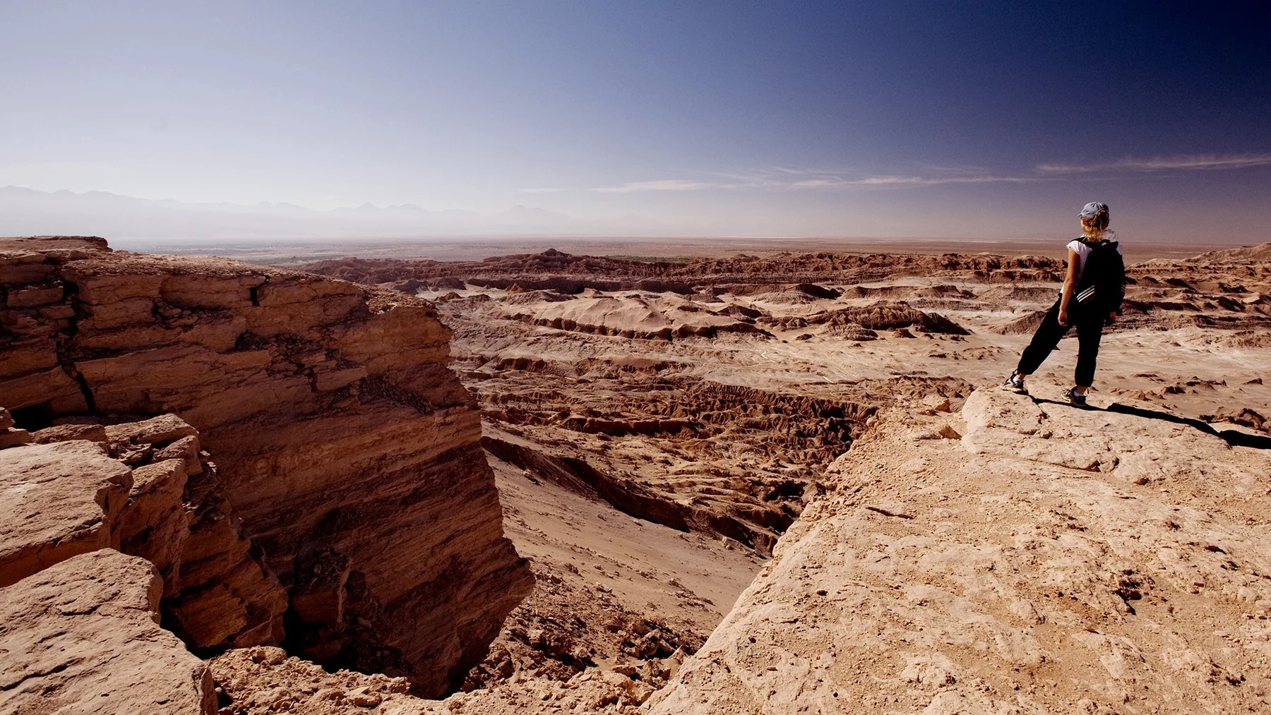 A hiker walks along a rocky ridge above the desert landscape near San Pedro de Atacama.
